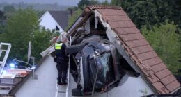 Police officer investigating a car crashed into a house.