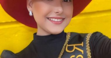 Portrait of Camila Trevisol, a rodeo queen, wearing a red cowboy hat and sash.