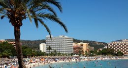 Crowded beach in Magaluf, Mallorca, with hotels in the background.