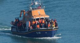 Migrants entering the water from a small boat.
