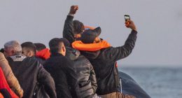Migrants in a small boat taking a selfie while crossing the English Channel.