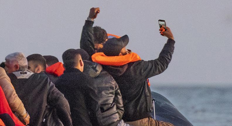 Migrants in a small boat taking a selfie while crossing the English Channel.