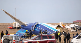 Plane crash at an airport with emergency personnel and onlookers.