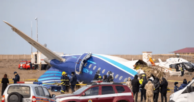 Plane crash at an airport with emergency personnel and onlookers.
