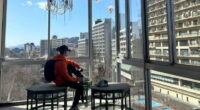 Person filming abandoned Japanese hotel overlooking other buildings.