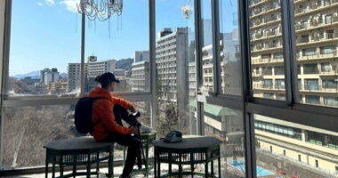 Person filming abandoned Japanese hotel overlooking other buildings.