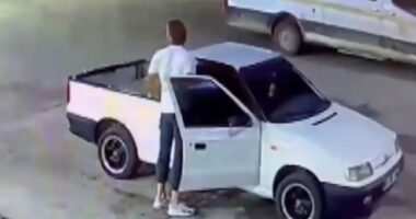 Screenshot of a video showing a person filling bottles with petrol, along with a van and a pickup truck.