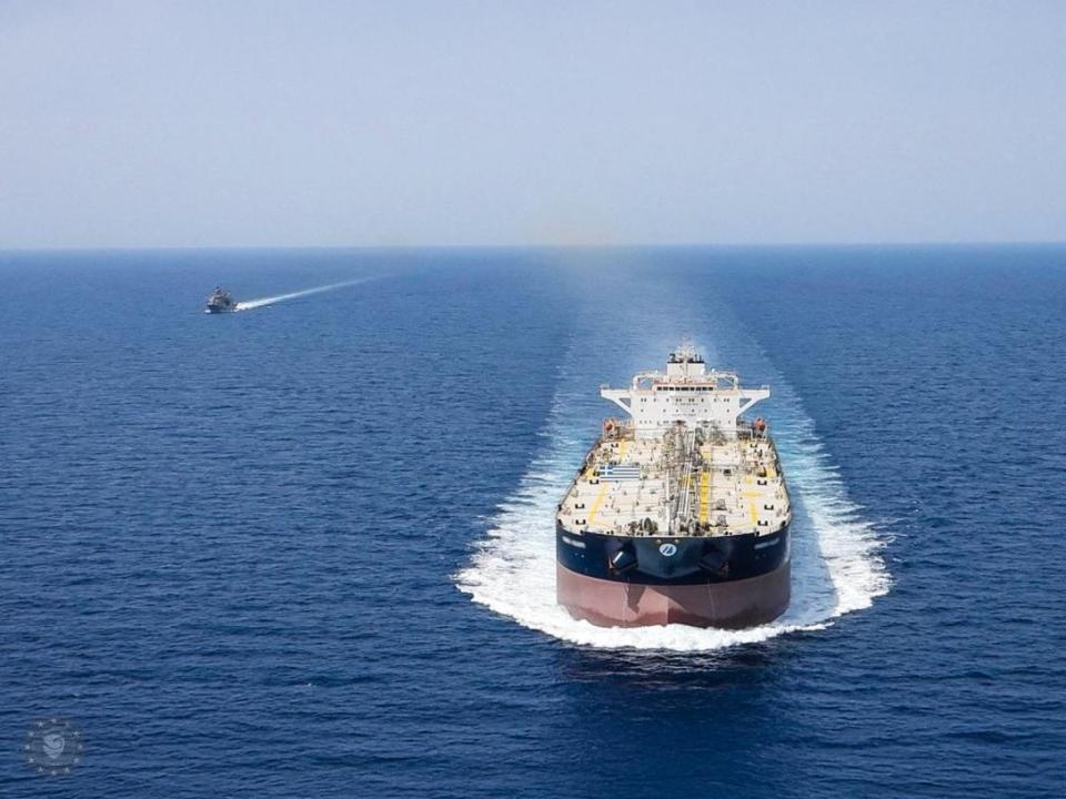A large tanker ship escorted by a smaller vessel on the open ocean.