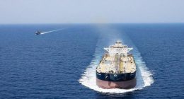 A large tanker ship escorted by a smaller vessel on the open ocean.