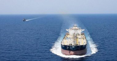 A large tanker ship escorted by a smaller vessel on the open ocean.