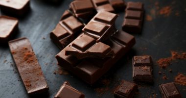 Broken pieces of dark chocolate on a dark surface.