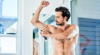 Man applying deodorant in a bathroom.