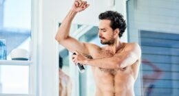 Man applying deodorant in a bathroom.