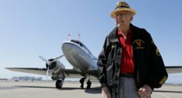 A D-Day veteran and a pilot holding hands.