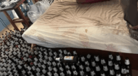 Many empty beer bottles surrounding a bed.