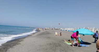 Beach scene with people sunbathing and swimming.