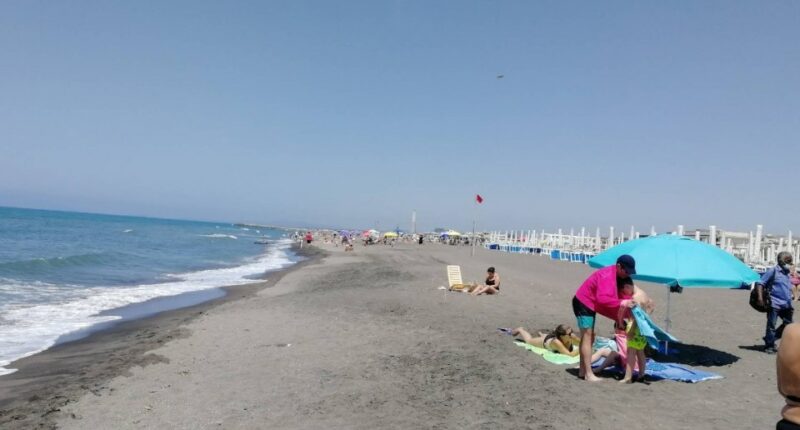 Beach scene with people sunbathing and swimming.