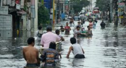 Residents wade through a flooded street in Malabon City, Philippines.
