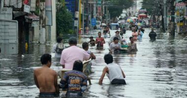 Residents wade through a flooded street in Malabon City, Philippines.