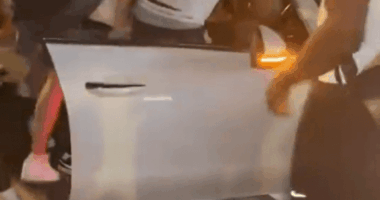 A gang surrounding a car, attacking the driver.