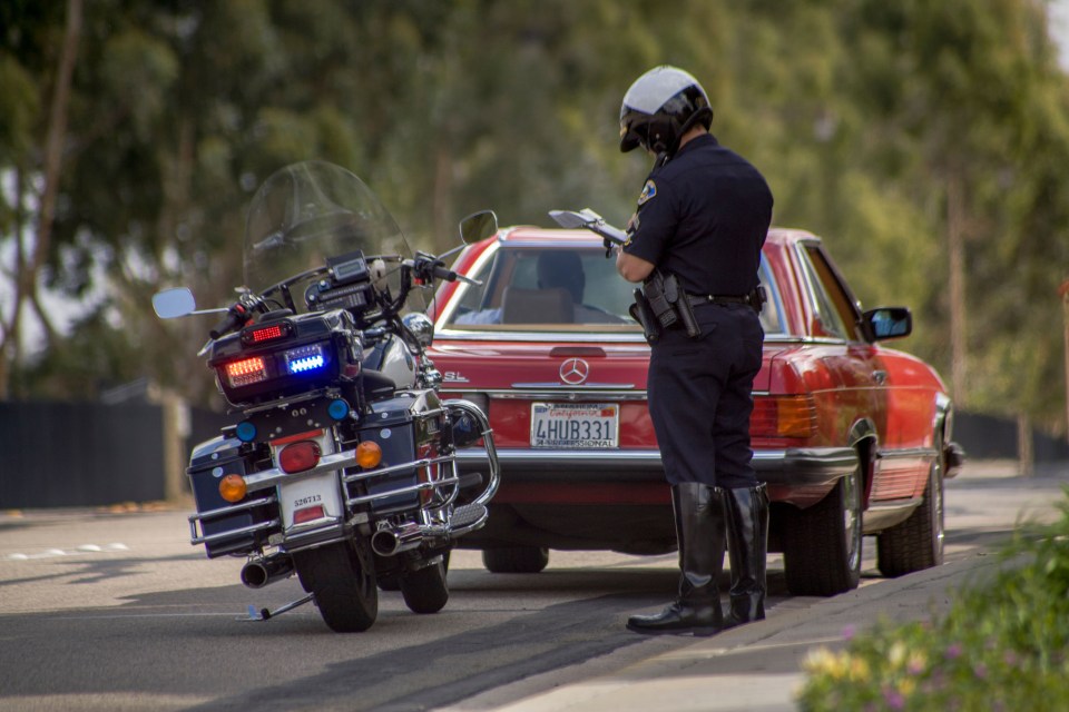 Motorcycle police officer writing a traffic ticket.