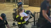 Firefighter carrying a person down steps.