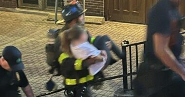 Firefighter carrying a person down steps.