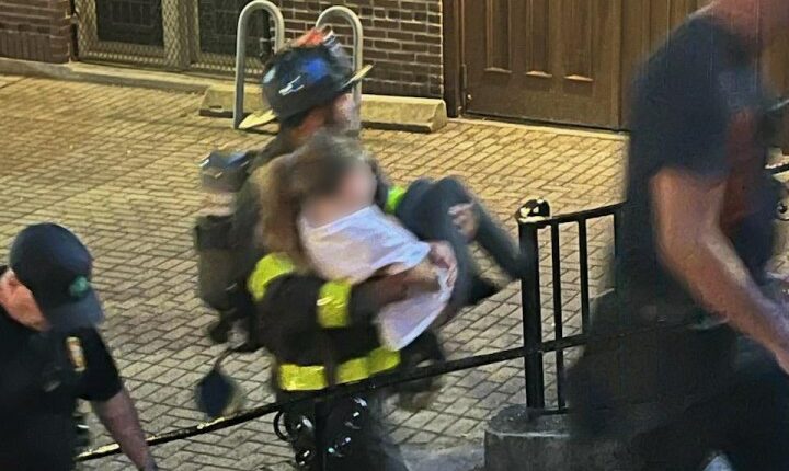 Firefighter carrying a person down steps.