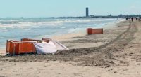 Beach scene with orange barriers and a white sheet near the water.