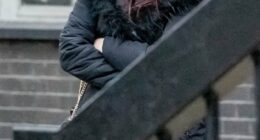 Woman in a black hooded coat with arms crossed.