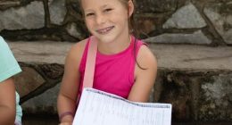 Girl sitting on steps holding papers.