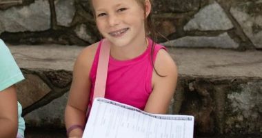Girl sitting on steps holding papers.