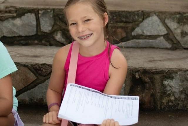 Girl sitting on steps holding papers.