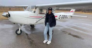 Woman standing in front of a small airplane.