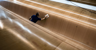 A worker cleaning the hull of a large yacht.