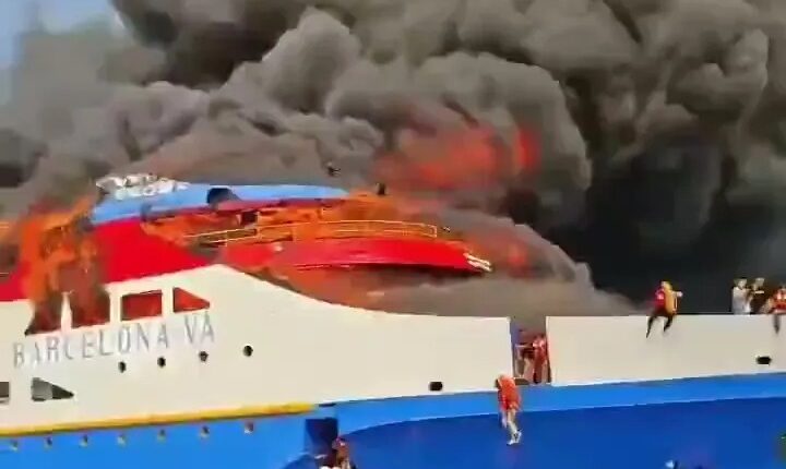 Burning ferry with people jumping into the ocean.