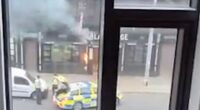 View from a window of a street scene with a small fire, police officers, and police cars.