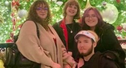 Photo of four friends in front of a Christmas tree.