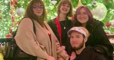 Photo of four friends in front of a Christmas tree.