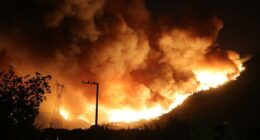 Large wildfire at night engulfing a hillside.