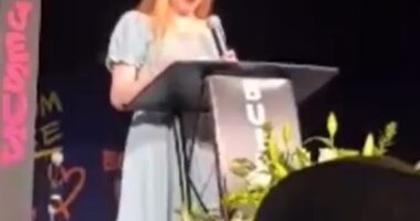 Teenage girl giving a speech at a podium.