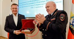 A pistol in a wooden box being presented to a man in a suit.