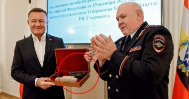 A pistol in a wooden box being presented to a man in a suit.