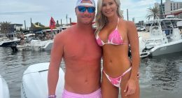 Couple in swimwear posing on a boat.