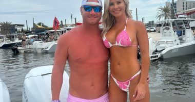 Couple in swimwear posing on a boat.