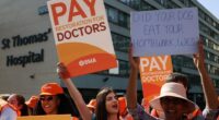 Resident doctors on strike holding signs advocating for better pay.
