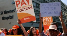 Resident doctors on strike holding signs advocating for better pay.