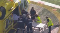 Paramedics loading a patient onto a stretcher next to a rescue helicopter.