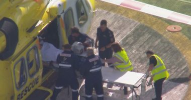 Paramedics loading a patient onto a stretcher next to a rescue helicopter.