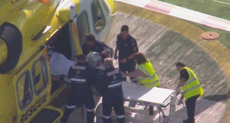 Paramedics loading a patient onto a stretcher next to a rescue helicopter.